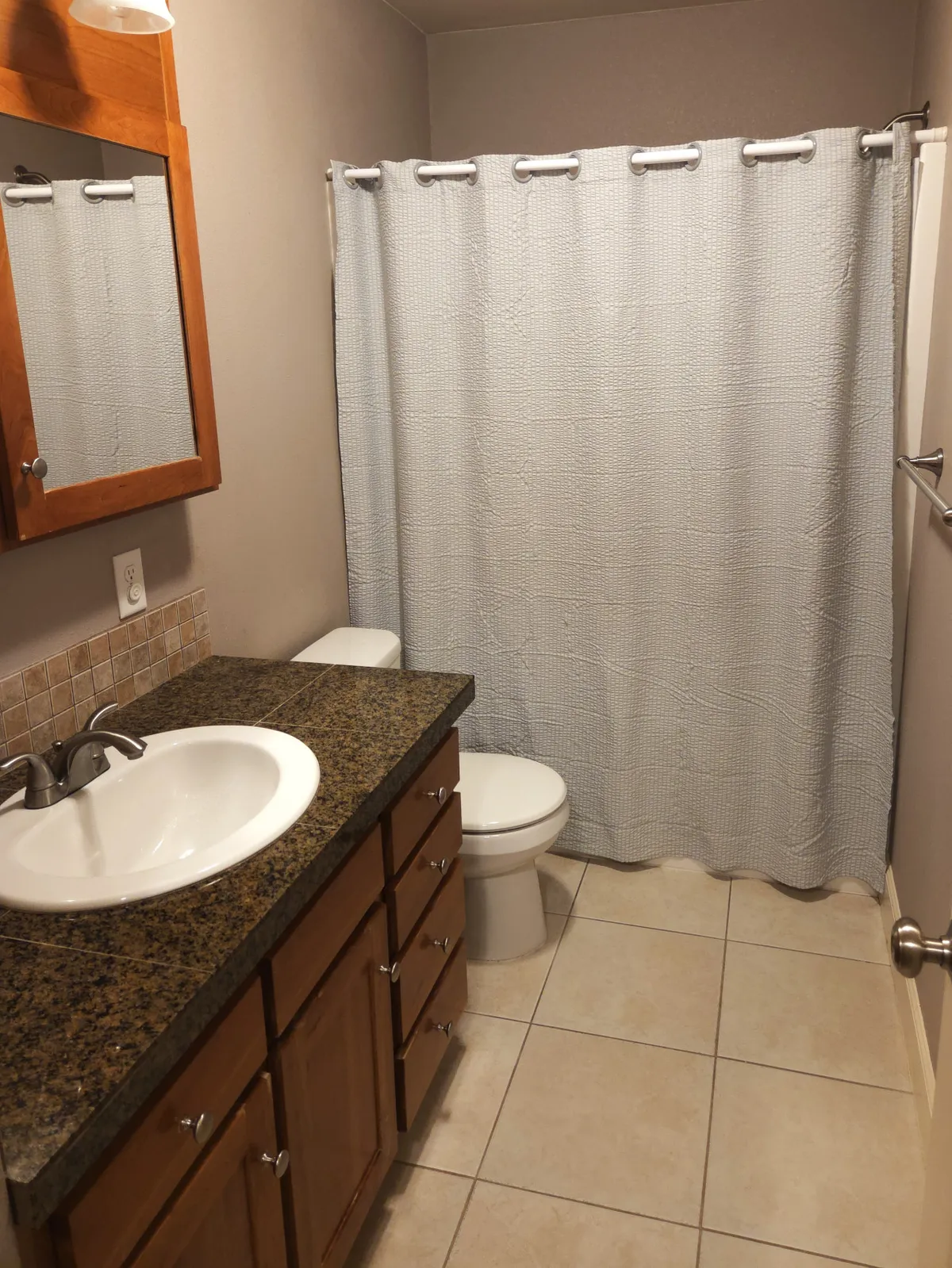 A refreshed bathroom with a vanity and sink, shower with curtain, mirror, and tiled walls. The space feels calm, clean, and ready for moments of personal care or relaxation.