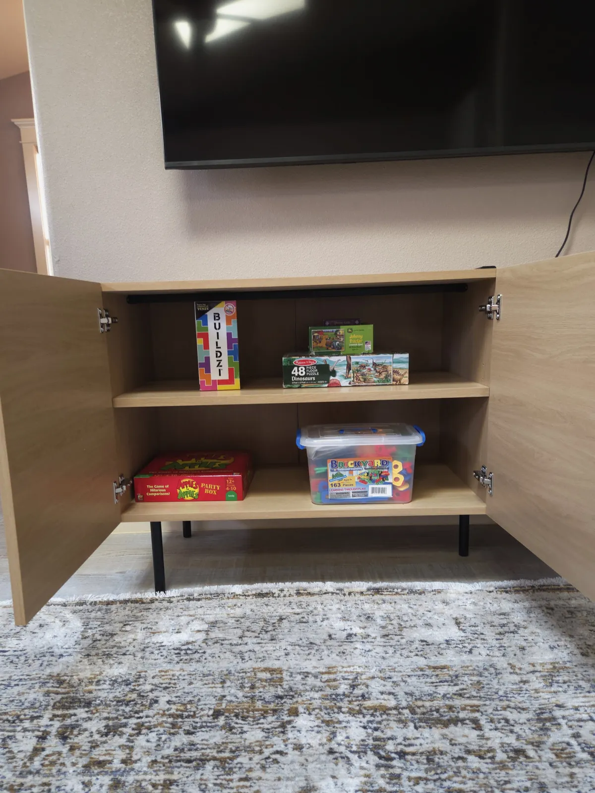 This cozy family room scene features a TV unit surrounded by board games and children's toys. The atmosphere is playful and inviting, conveying a sense of togetherness where families can unwind with games or movie nights after a day out.